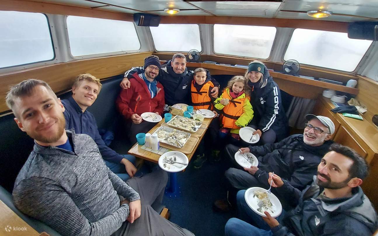 Smiling passengers share a meal, enjoying their freshly caught fish