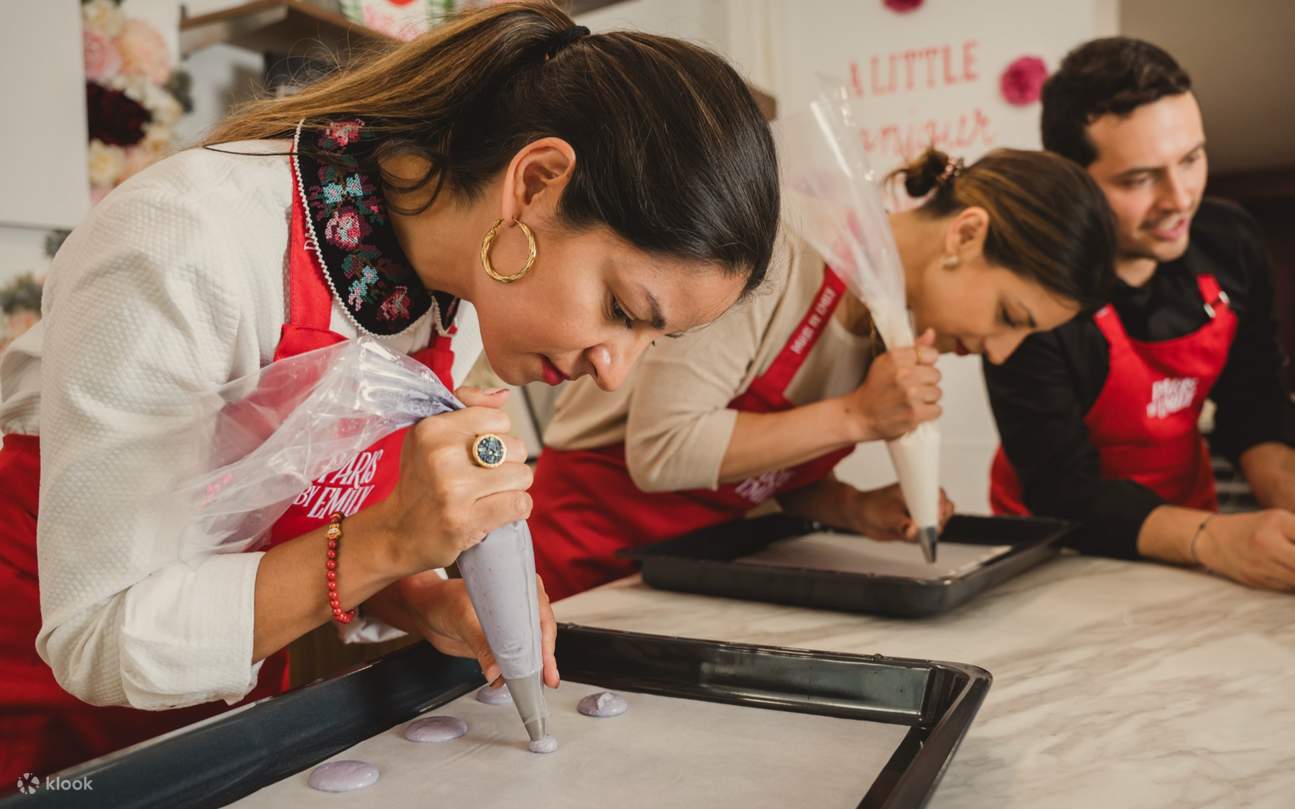 Konzentrierte Teilnehmer spritzen ihren Teig sorgfältig auf Bleche und erwecken so ihre eleganten Macaron-Kreationen zum Leben.