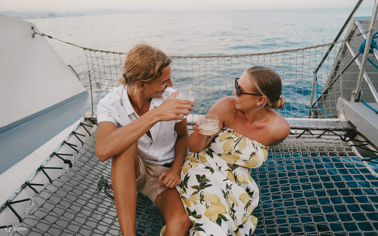 Una pareja feliz descansa en la cubierta, riendo juntos mientras disfrutan de coloridos y refrescantes cócteles.