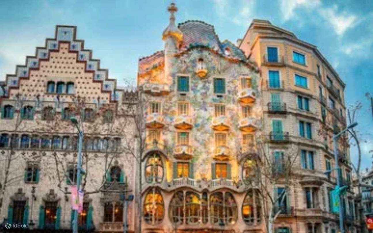 Bus melewati bangunan-bangunan monumental Barcelona, menampilkan arsitektur bersejarah di bawah sinar matahari Mediterania yang cerah