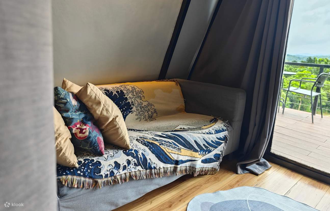 Серый диван с несколькими подушками рядом со стеклянной дверью