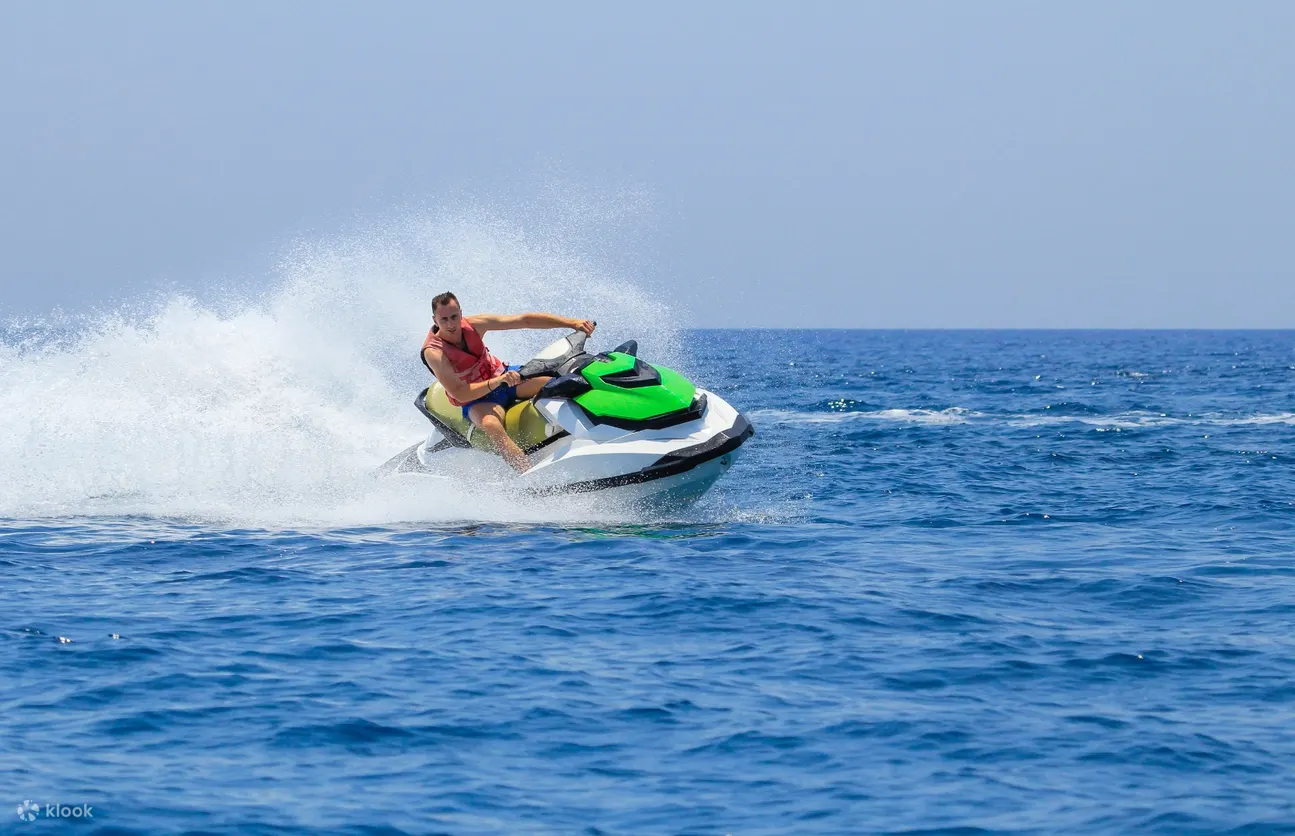 person with a life vest riding a green jet ski