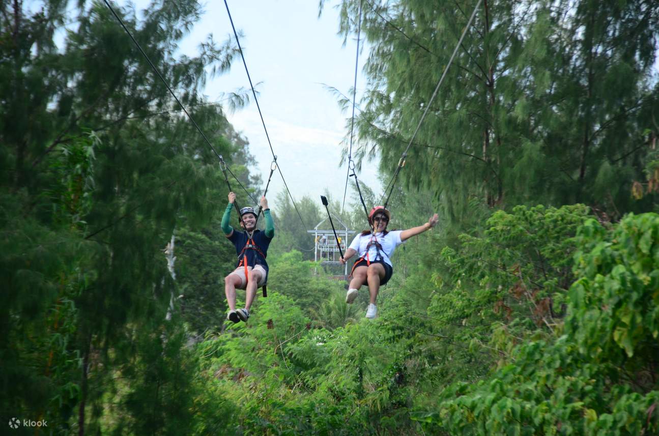 Two people riding the dual zipline
