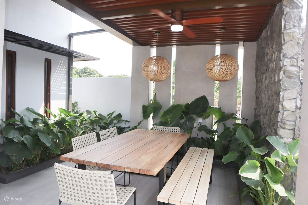 テーブル、椅子、緑豊かな植物で飾られた静かなパティオが、静かな屋外空間を作り出しています