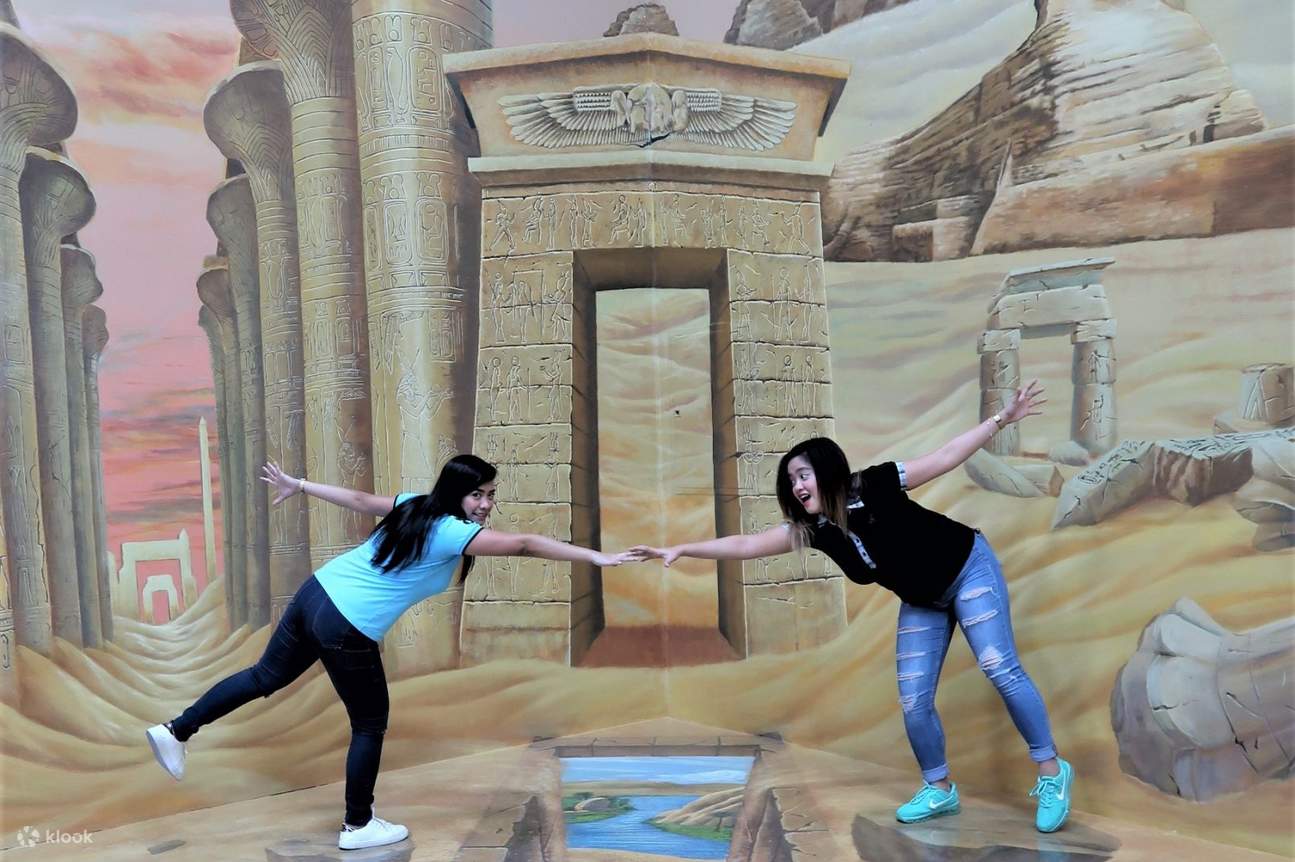 두바이 3D 아트 뮤지엄에서 땅에 있는 구멍을 내려다보고 있는 두 소녀