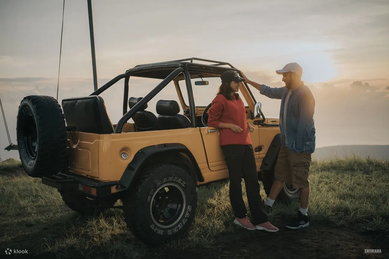 a couple is chatting beside the jeep