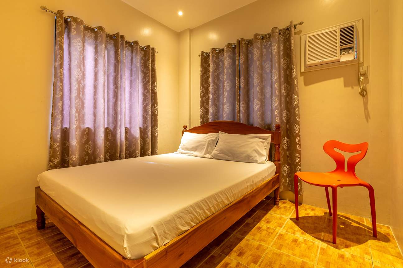 Una camera da letto accogliente con un letto confortevole, una sedia e un condizionatore d'aria