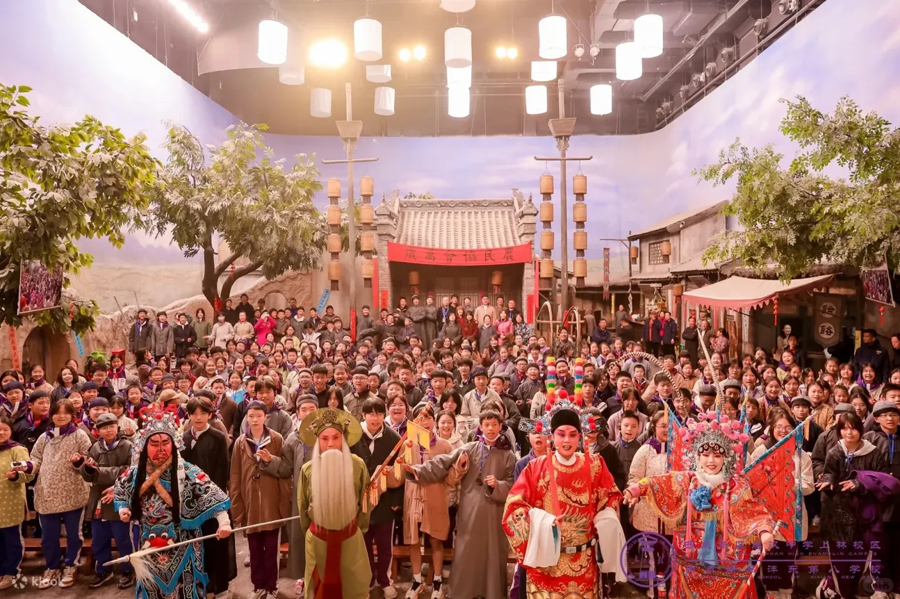 以关中古建为背景，戏曲演员身着华丽戏服，与众多游客同框。融合传统戏曲表演与沉浸式场景，展现影视城 “文旅 + 非遗 + 研学” 的多元体验，让游客在古街氛围中感受关中文化魅力，传递民俗传承与互动乐趣