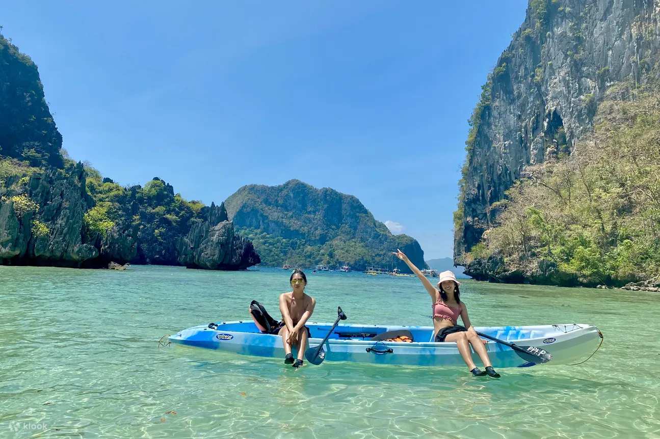 2 people on a kayak in the ocean with rock formations in the background
