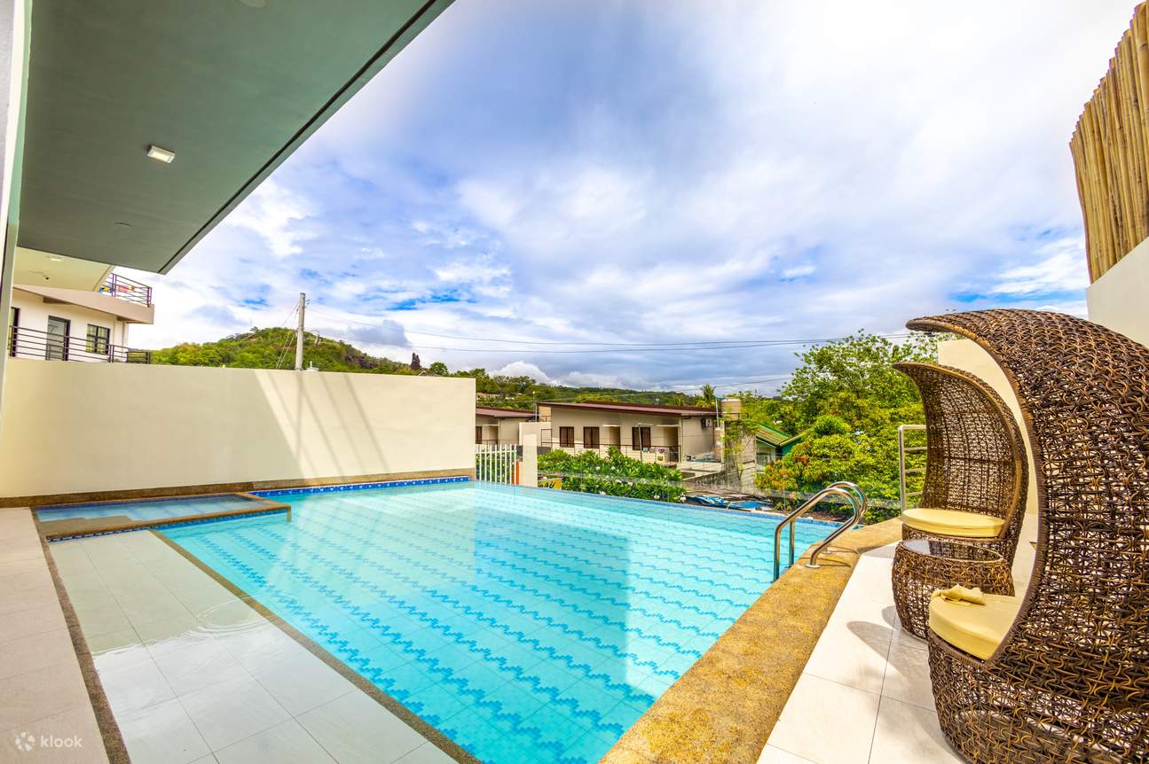 밝고 푸른 수영장과 그 옆에 놓인 두 개의 라운지 의자