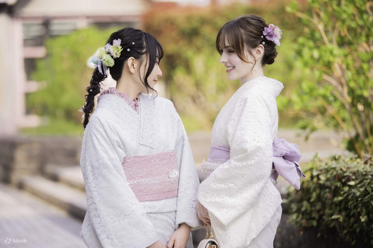 tiga teman mengenakan kimono berjalan di bawah pepohonan