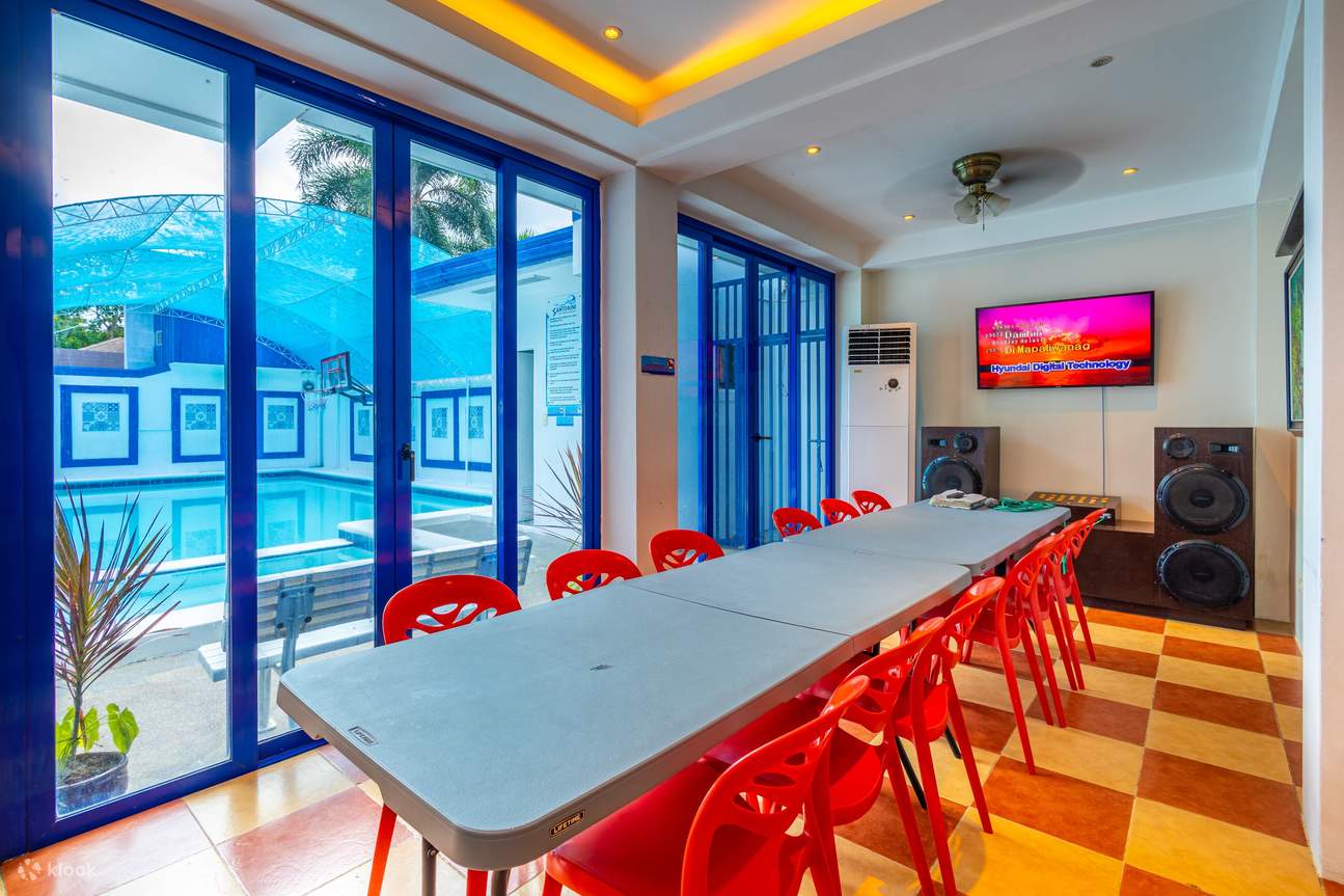 Una sala da pranzo con tavolo, sedie rosse e impianto karaoke