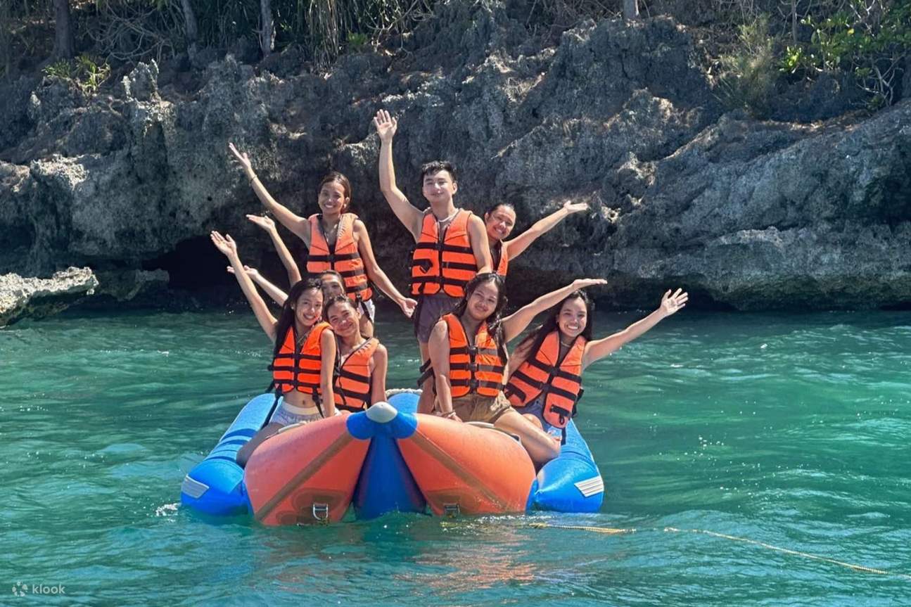 Sekelompok orang menaiki banana boat di atas perairan berwarna pirus