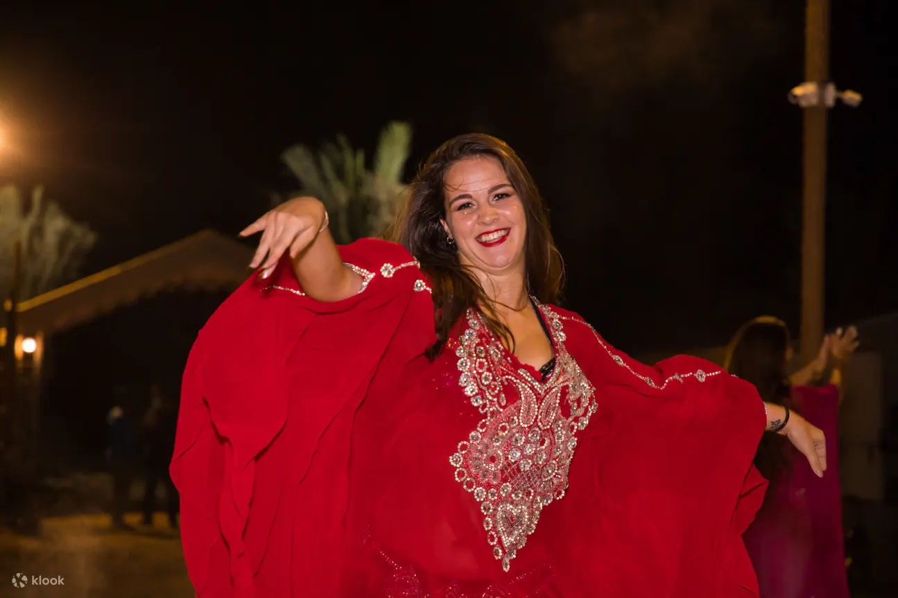 một người phụ nữ mặc abaya đỏ nhảy múa ở trại sa mạc