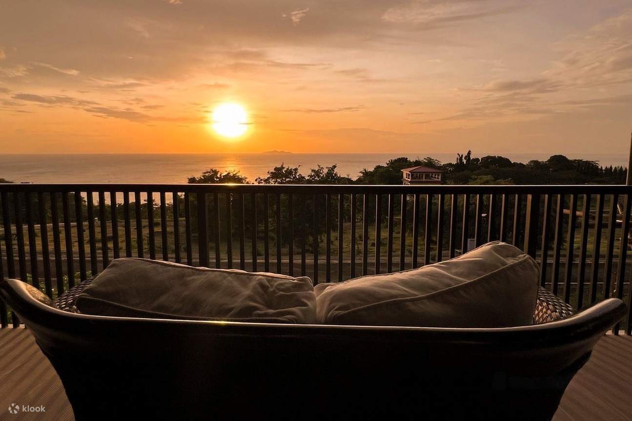 kursi di balkon, menghadap ke laut saat matahari terbenam