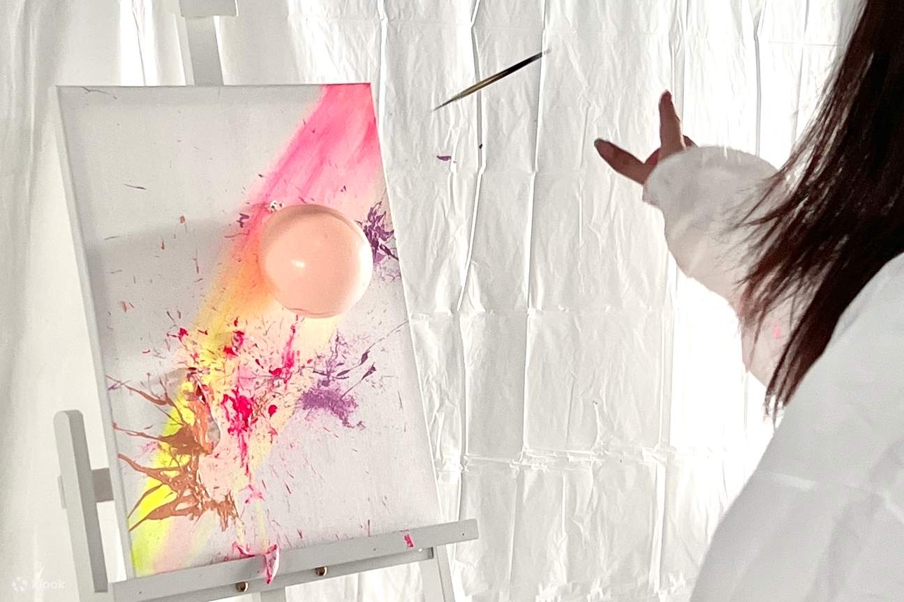 seorang wanita memercikkan cat dengan meletuskan balon