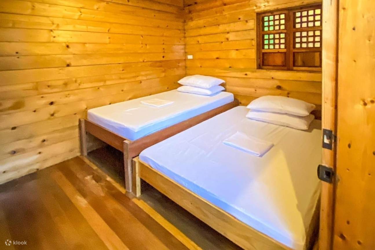 舒适的木屋里有两张铺着白色床单的床，营造出宁静而温馨的氛围