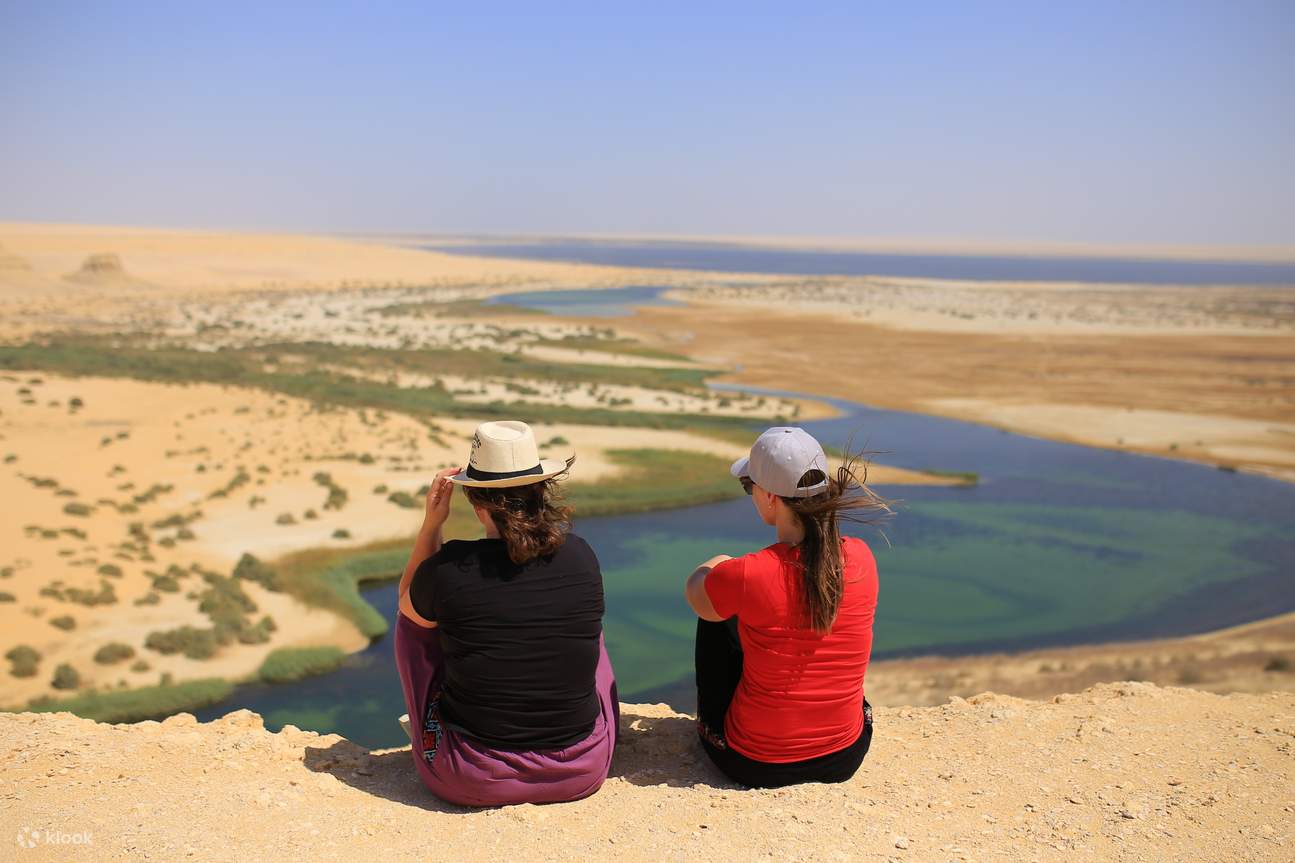 dua wanita bertopi menghadap padang pasir di kairo