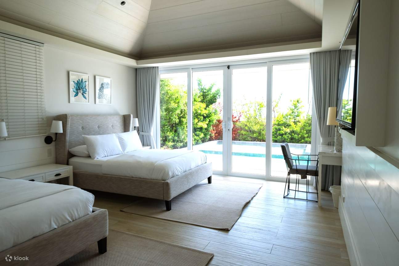 Un dormitorio con dos camas cómodas y vistas a una piscina resplandeciente