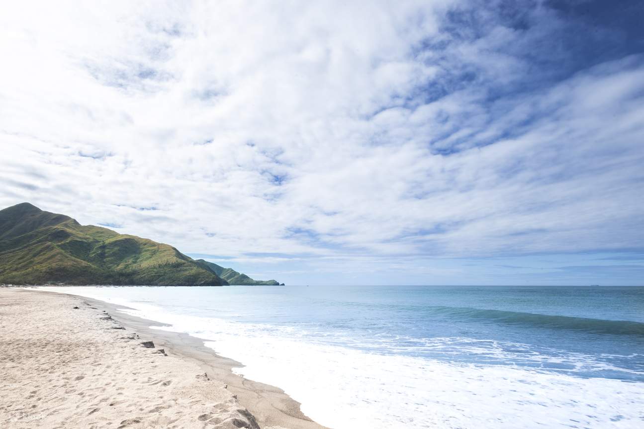 海滩，背景是海洋和连绵起伏的丘陵