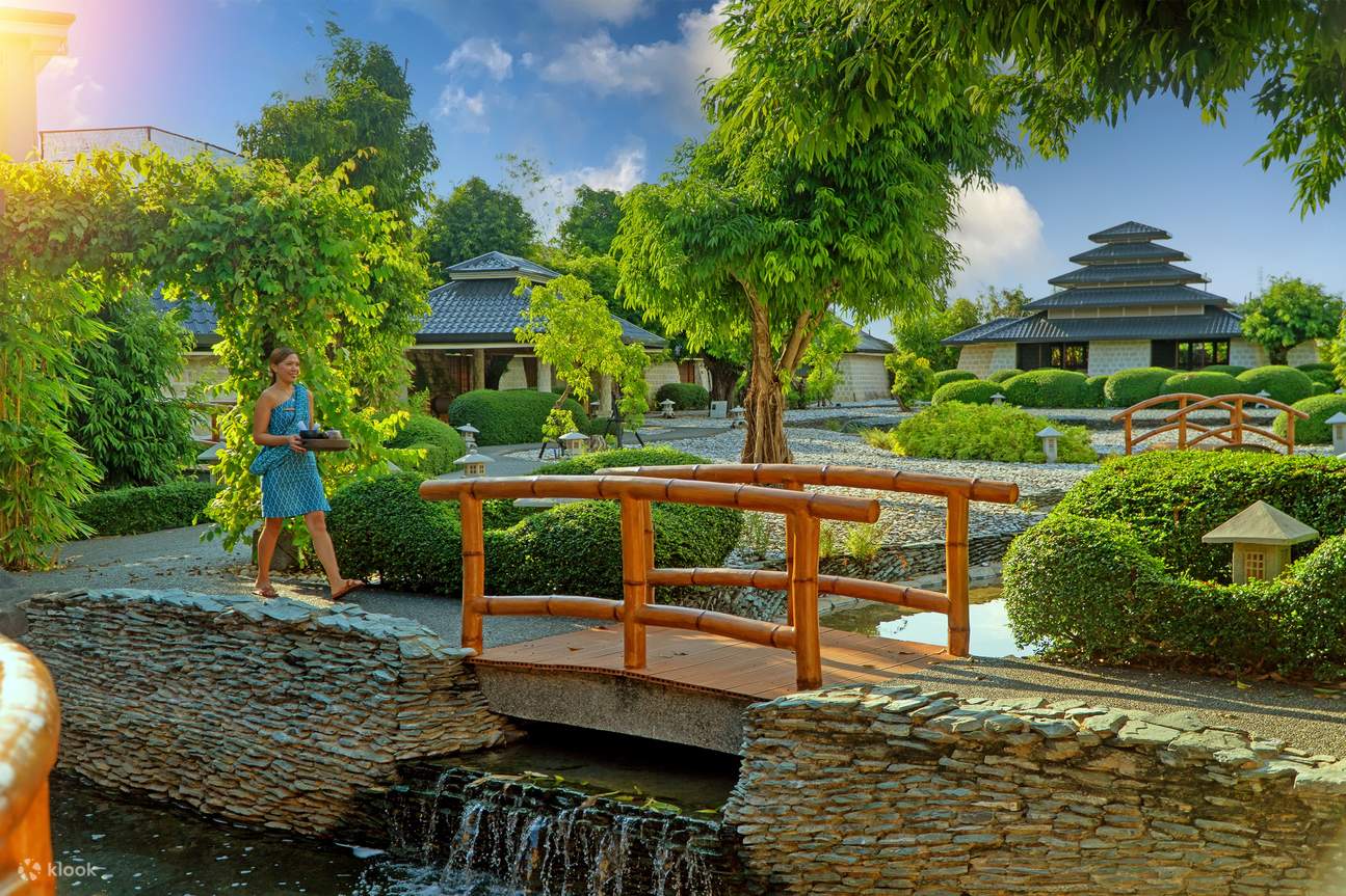 Pemandangan taman bergaya Jepang di Plantation Bay dengan petugas spa berjalan membawa peralatan spa