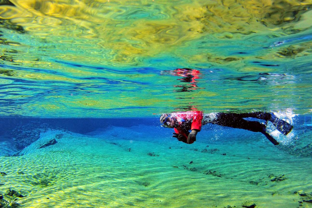 Một người đàn ông mặc đồ bơi màu đỏ đang lặn biển ở Silfra