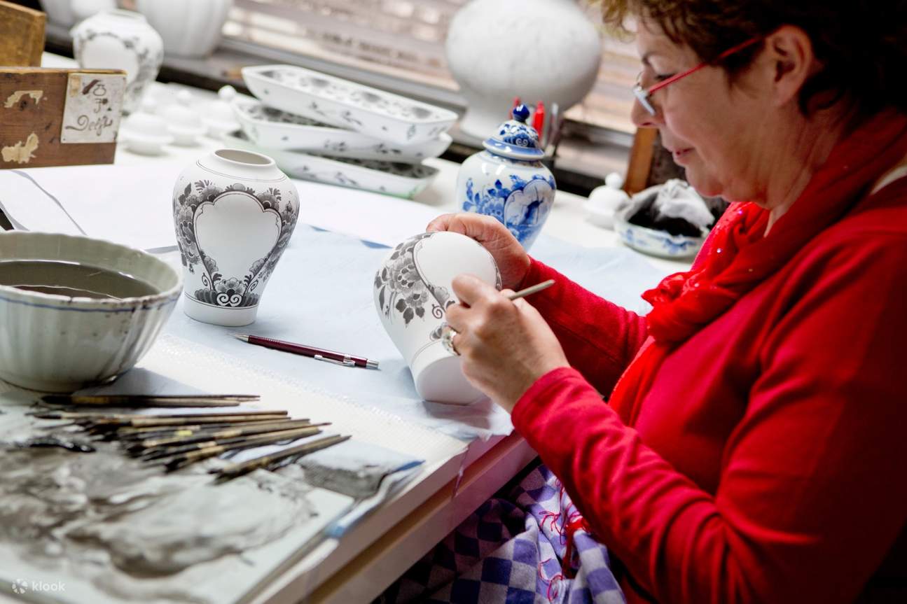artist painting on pieces of earthenware by delft blue