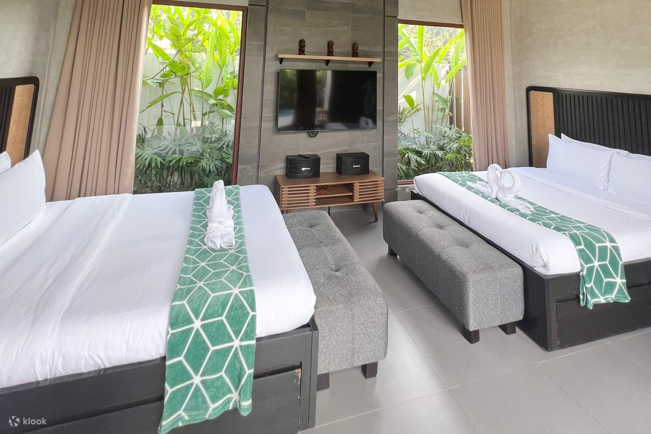 部屋にテレビ付きのベッド 2 台と緑と白のベッドカバー