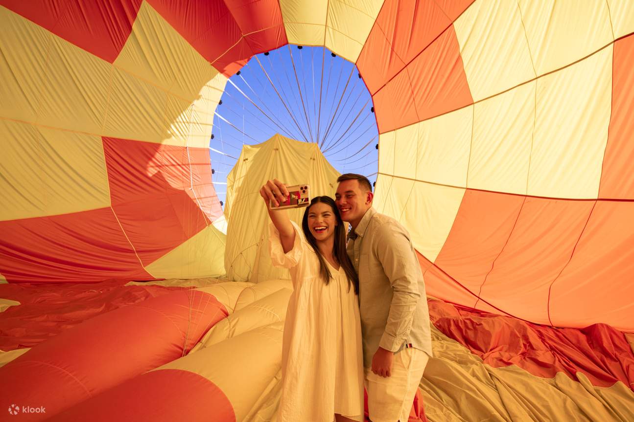 couple taking picture under hot air balloon
