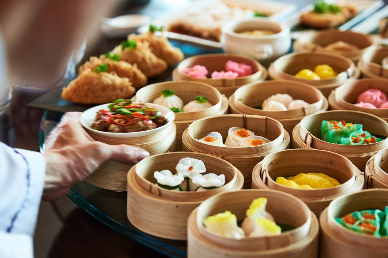 Ein Mann, der ein Tablett mit Dim Sum hält, einer traditionellen chinesischen Küche, mit einer Auswahl an mundgerechten, gedämpften oder gebratenen Teigtaschen und Snacks