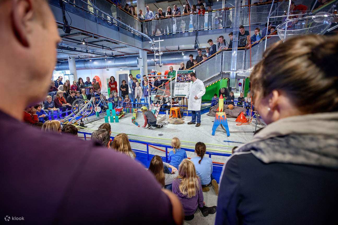 seorang saintis bercakap di hadapan penonton yang terdiri daripada keluarga