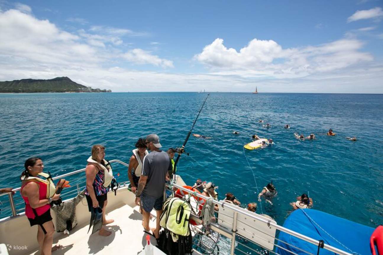 Teman-teman berkumpul di dek katamaran, menikmati pemandangan laut dan angin laut yang sepoi-sepoi
