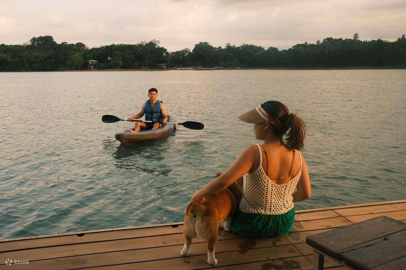 man kayaking while a woman and pet dog sit by the edge of the floating house
