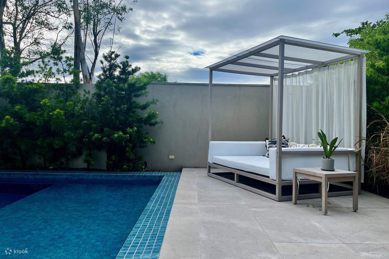 Một chiếc giường canopy trắng ấm cúng bên hồ bơi lấp lánh, tạo nên một bầu không khí thanh bình và sang trọng