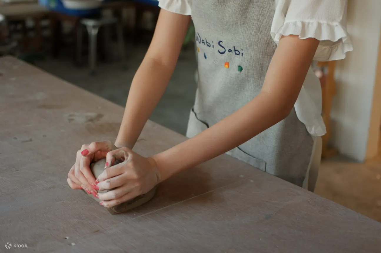 Person shaping their clay on a wooden table