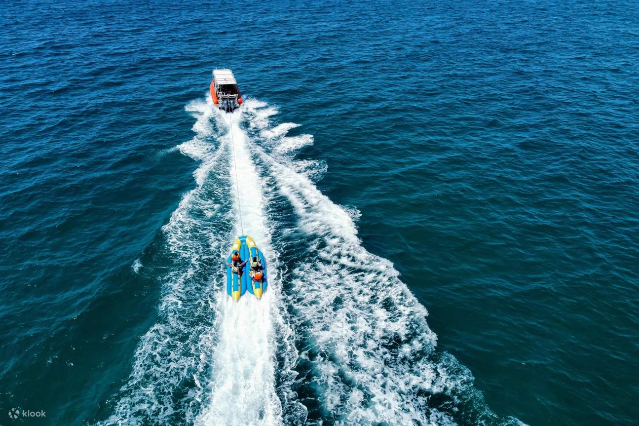 Sebuah speedboat bergerak melintasi lautan sambil menarik banana boat