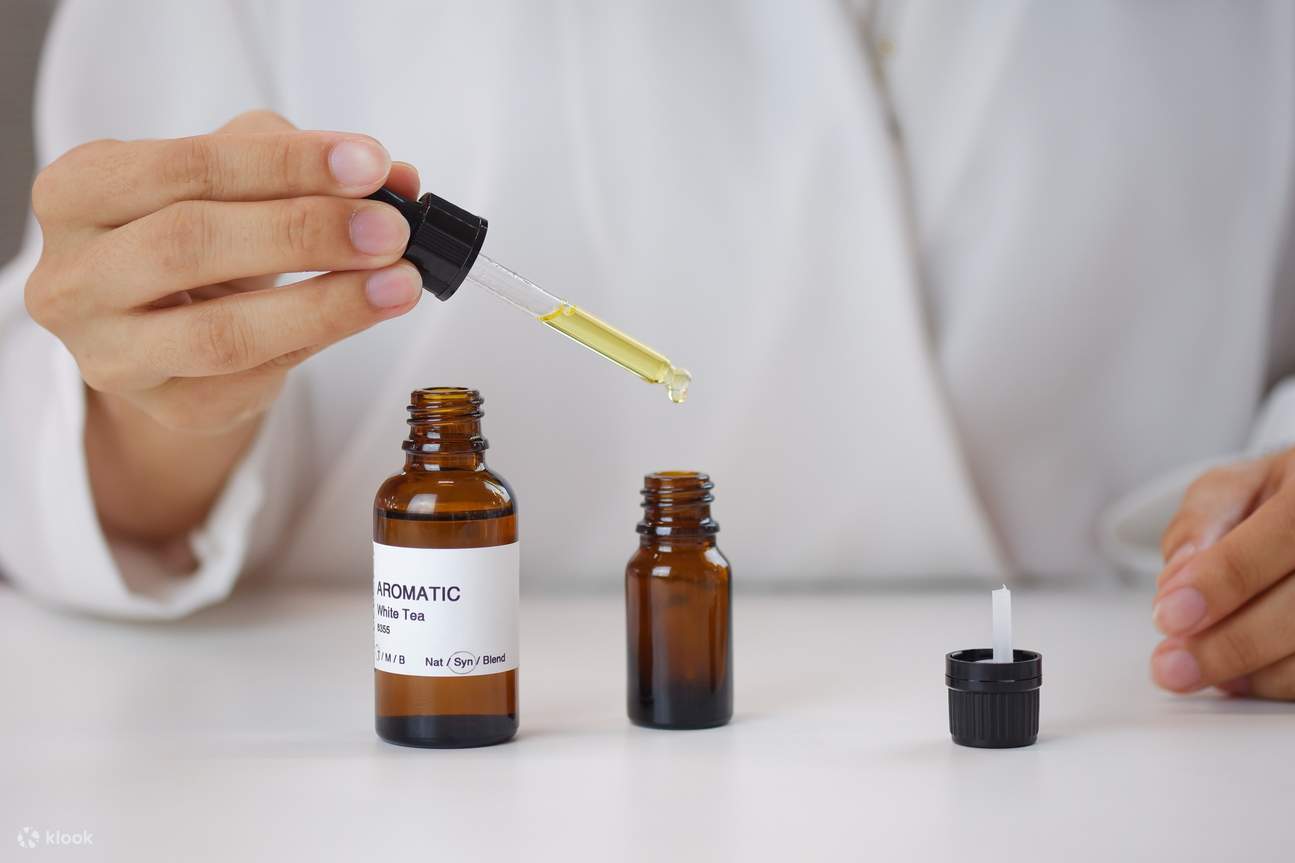 Une personne ajoutant de l'huile essentielle dans un flacon de parfum à l'aide d'un compte-gouttes