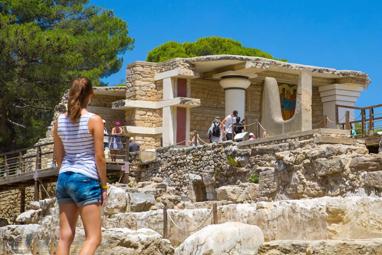 Un visitante caminando hacia la entrada parcialmente restaurada del Palacio de Knossos
