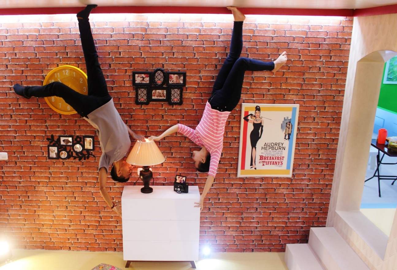 a couple posing upside down inside a living room themed space