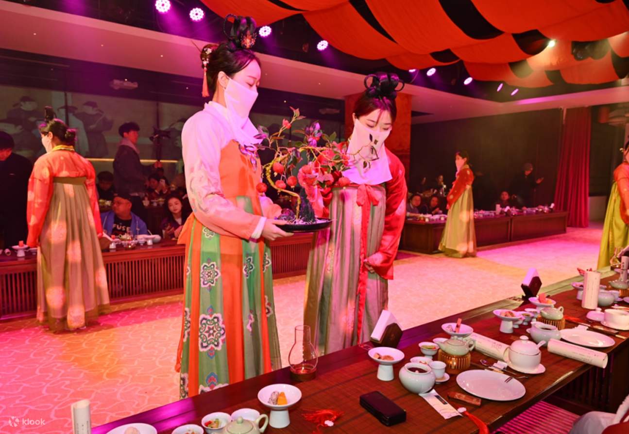 Two palace maids dressed in dark cyan Ruqun dresses walked slowly onto the stage, holding gold-traced trays in their hands. On the trays were soup bowls covered with silver lids, and brocade embroidered with dragon patterns hung on both sides of the trays