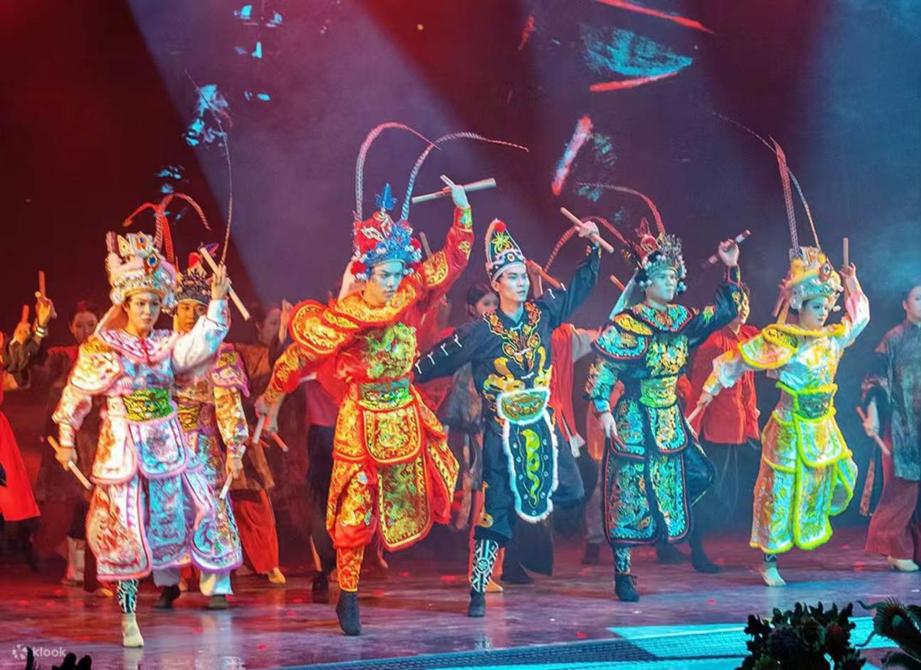 Die in traditionellen Opernkostümen gekleideten Schauspieler heben die Arme, halten Stöcke, bunte Kleidung kombiniert mit roten und violetten Lichtern und Schatten, die Bewegungen sind ordentlich und voller Bühnenpräsenz.