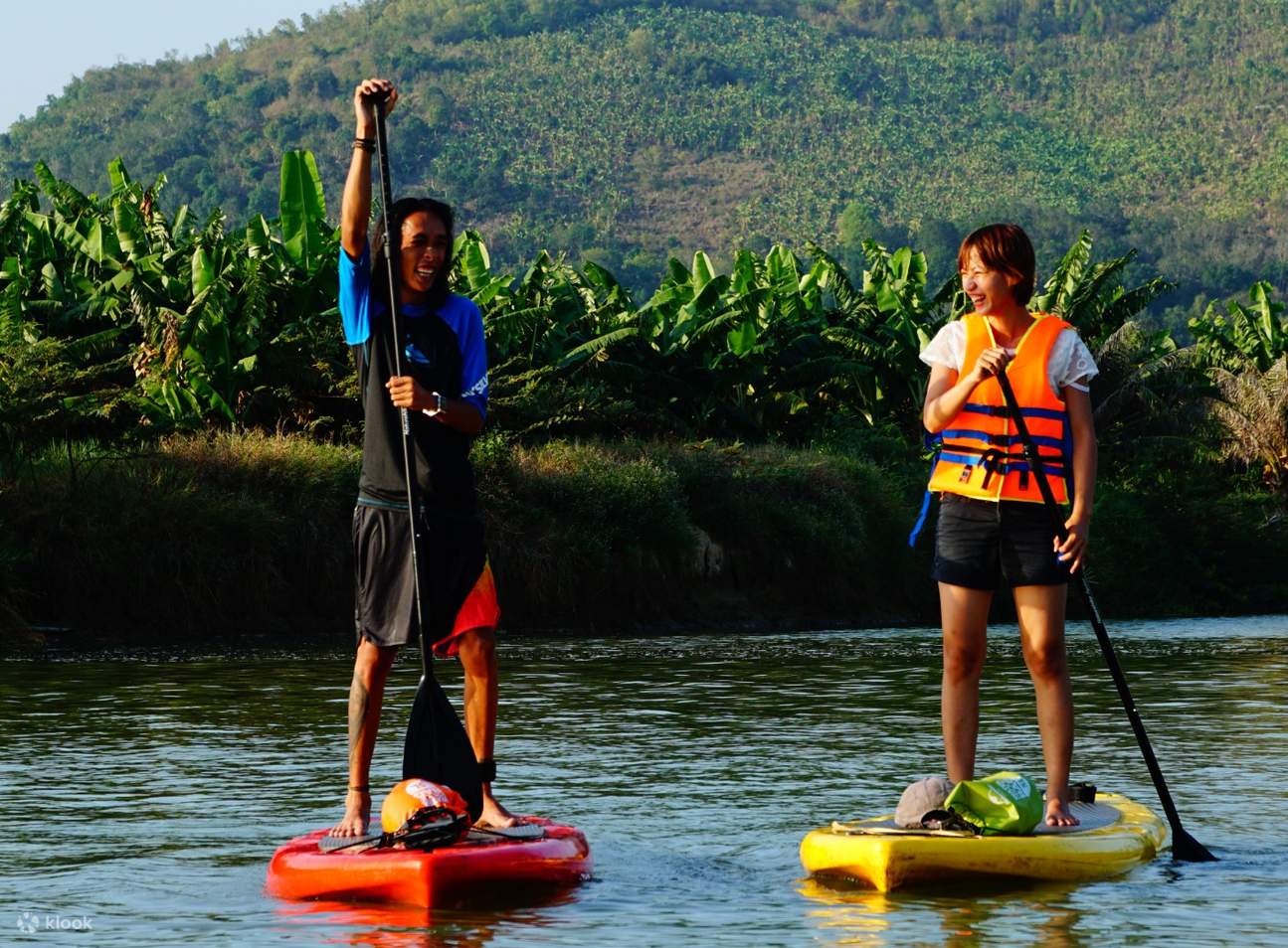 two persons stand up paddleboarding in cai river