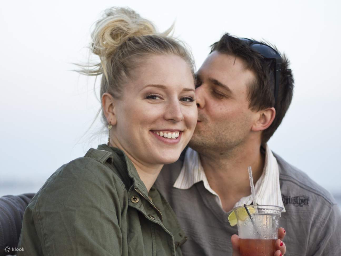 Ein leises Lachen teilend, genoss das Paar mit einem Lächeln seine Willkommenscocktails mit Blick auf den Hafen.