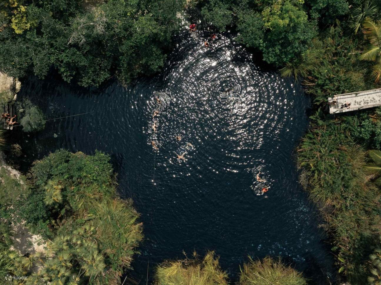 Ein Guide führt Entdecker durch den Eingang einer heiligen Cenote, der die Bedeutung der Maya-Unterwelt widerspiegelt