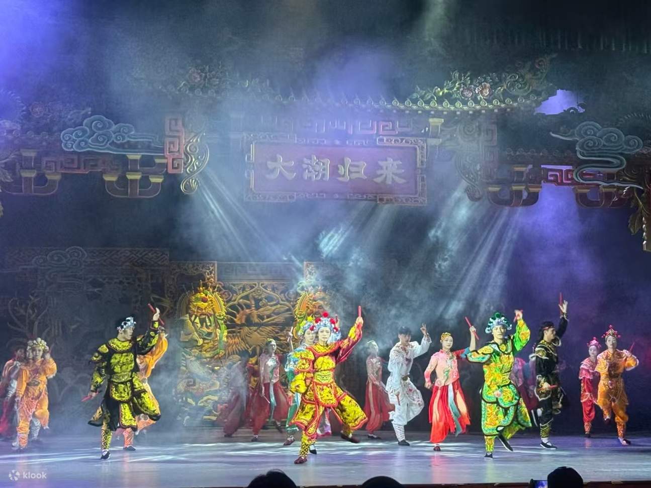 Die Schauspieler tanzen in prächtigen Kostümen der chinesischen Oper, während das Schild „Die Rückkehr der großen Flut“ von farbenfrohen Lichtern untermalt wird. Tradition und modernes Bühnengefühl vereinen sich.