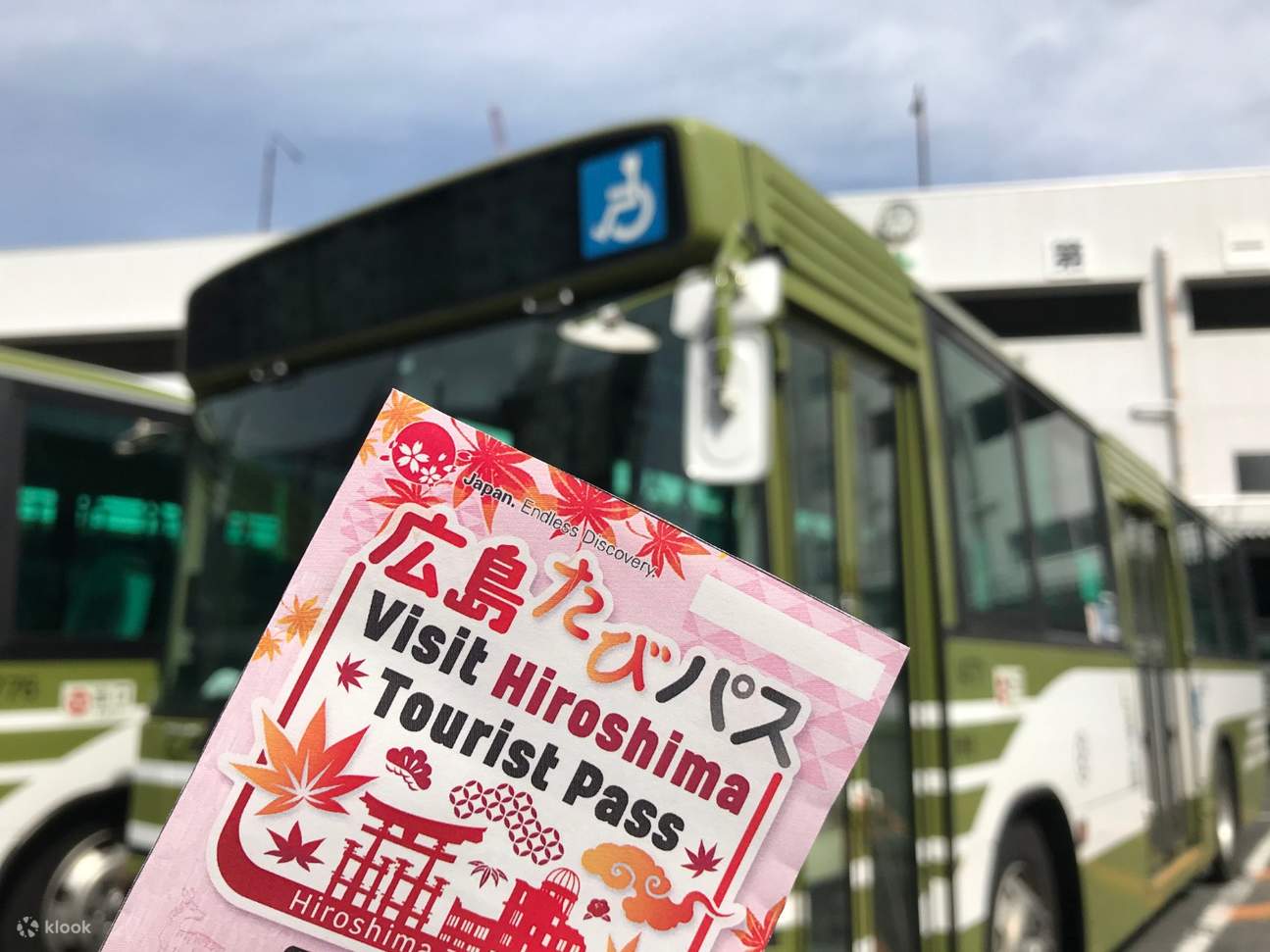 Hiroshima Tourist Pass being held up; there's a view of a bus