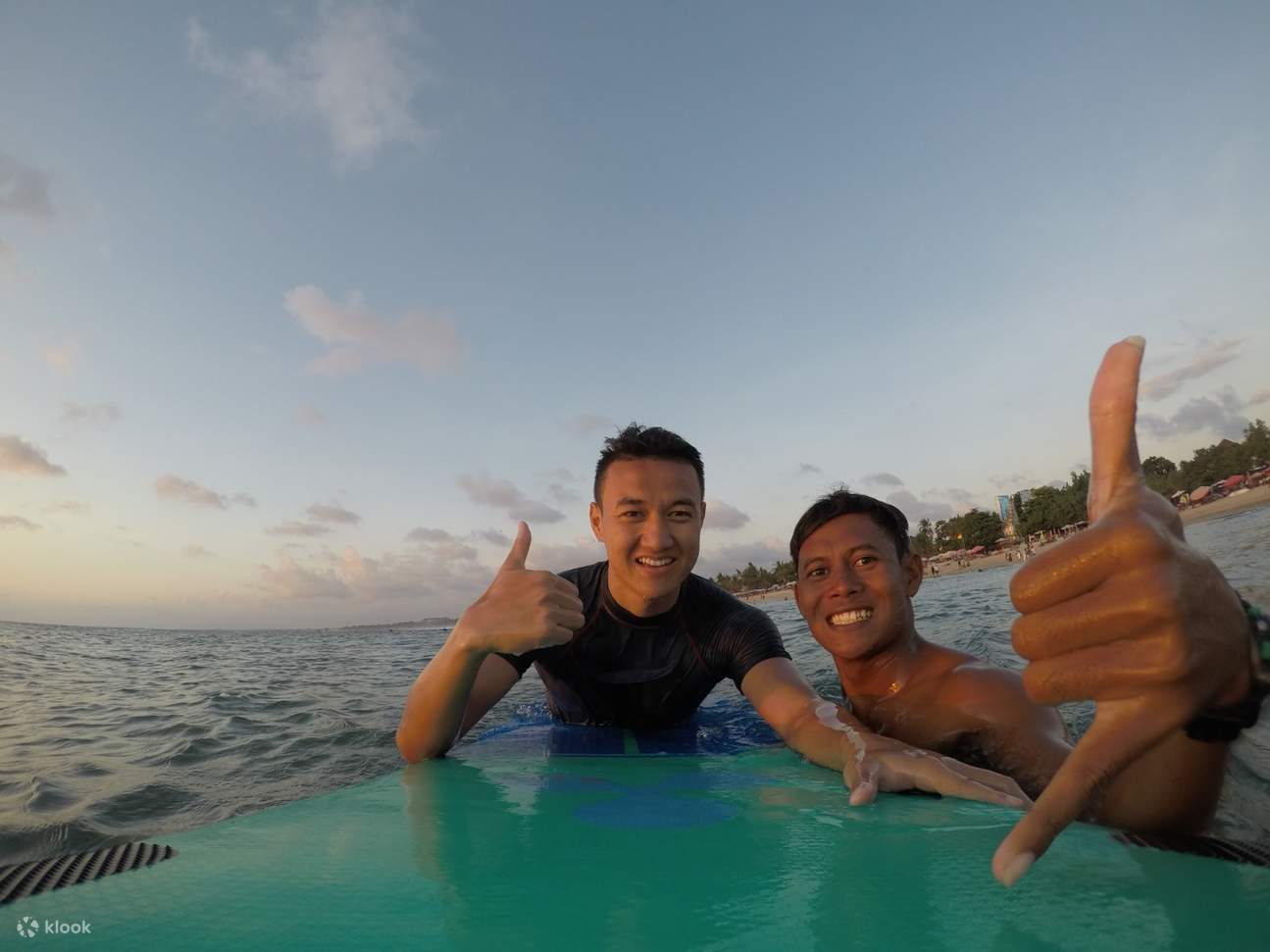 two men posing while holding a surf board