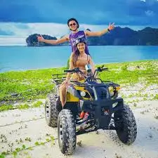 一对年轻夫妇在沙滩上享受他们的 ATV 骑行
