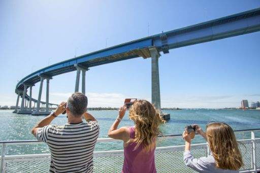 Penumpang teruja menggunakan binokular untuk melihat dengan lebih dekat penampakan ikan paus dari jauh
