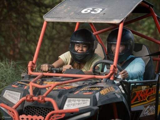 Conductor con casco navegando por un estrecho sendero para vehículos todo terreno rodeado de una densa vegetación tropical